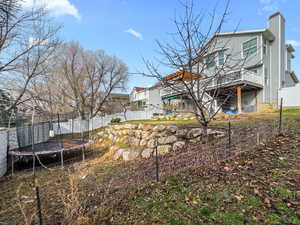 Back of house featuring a fenced backyard, a chimney, a trampoline, and a deck