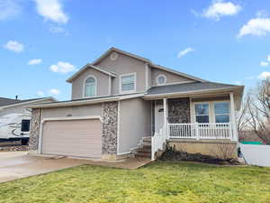 Traditional home with covered porch, an attached garage, stucco siding, concrete driveway, and a front lawn