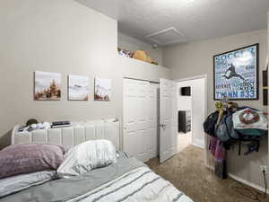 Bedroom featuring a closet, dark carpet, and a textured ceiling