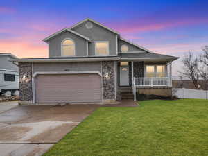 Traditional home featuring covered porch, driveway, a garage, brick siding, and stucco siding