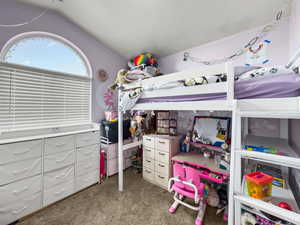 Bedroom with dark colored carpet and vaulted ceiling