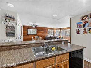 Kitchen with dishwasher, wood finish cabinets, ceiling fan, open floor plan, and dark wood-style floors