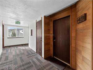 Hall featuring dark colored carpet and wood walls