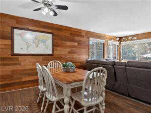 Dining space with wooden walls, dark wood-style floors, and a ceiling fan