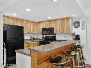 Kitchen featuring a kitchen bar, a peninsula, black appliances, recessed lighting, and light countertops