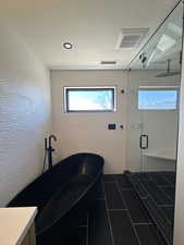 Full bathroom with a stall shower, a soaking tub, and a textured ceiling