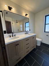 Full bath featuring double vanity, a stall shower, and dark tile patterned floors