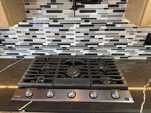 Kitchen view of tasteful backsplash, stainless steel gas range, and dark stone counters