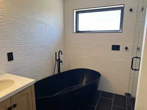 Bathroom with vanity, a freestanding tub, tile patterned floors, and a stall shower