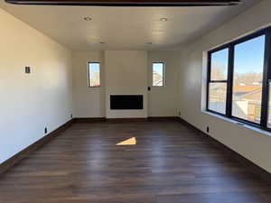 Unfurnished living room with dark wood-type flooring, recessed lighting, and a fireplace