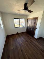 Unfurnished bedroom featuring dark wood-style floors, a closet, ceiling fan, and a textured ceiling