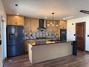 Kitchen with black appliances, dark wood-style flooring, an island with sink, tasteful backsplash, and decorative light fixtures