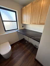 Laundry area featuring dark wood-style flooring and cabinet space