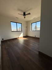 Empty room featuring dark wood-type flooring and ceiling fan