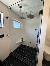 Full bath featuring a shower stall and dark tile patterned floors