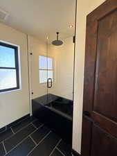 Full bath with dark tile patterned floors and baseboards
