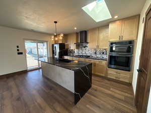 Kitchen featuring a skylight, double wall oven, backsplash, dark wood finished floors, and stainless steel fridge with ice dispenser