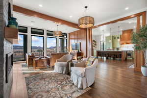 Living area featuring a mountain view, dark wood-style flooring, a fireplace, beam ceiling, and recessed lighting