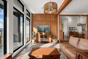 Living room with wood finished floors, a chandelier, and wooden walls