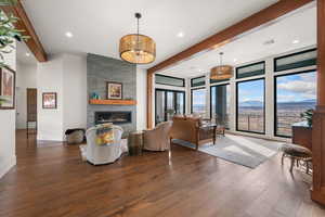 Living room featuring a mountain view, hardwood / wood-style flooring, a stone fireplace, recessed lighting, and beamed ceiling