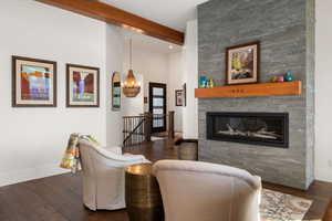 Living room with dark wood finished floors, a fireplace, a chandelier, and a high ceiling
