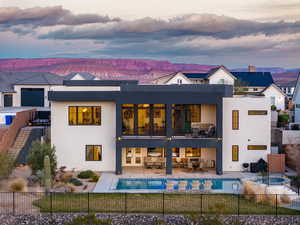 Back of house at dusk featuring stucco siding, a patio, and a fenced backyard