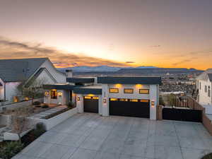 View of front facade featuring a garage, stucco siding, a patio area, and driveway