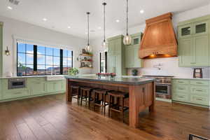 Two tone kitchen with a kitchen island, stainless steel appliances, dark wood finished floors, a breakfast bar area, and two tone cabinetry