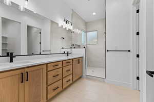 Full bathroom with double vanity, walk in shower, and light tile patterned floors