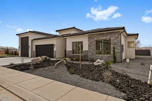 Prairie-style house featuring a garage, stucco siding, stone siding, concrete driveway, and a tile roof