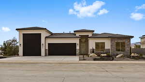 Prairie-style house featuring stone siding, an attached garage, stucco siding, driveway, and a tiled roof