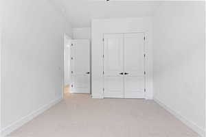 Unfurnished bedroom with light carpet and a closet