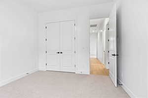 Unfurnished bedroom with light carpet and a closet