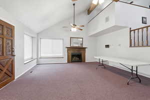 Unfurnished living room featuring dark colored carpet, a fireplace, vaulted ceiling, and ceiling fan