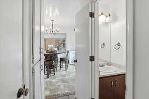 Bathroom featuring vanity, a textured ceiling, a chandelier, and stone finish floors