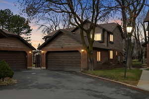 View of front of property featuring driveway, brick siding, a front lawn, roof with shingles, and an attached garage