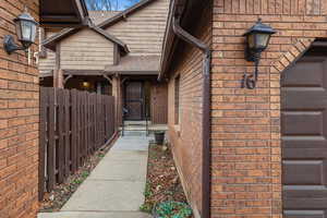 Doorway to property with brick siding and roof with shingles