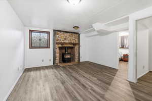 Unfurnished living room featuring a wood stove and light wood-style floors