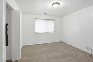 Carpeted spare room featuring baseboards and a textured ceiling