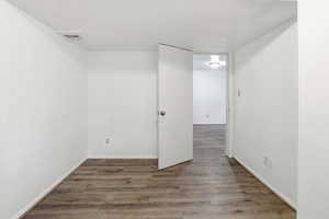 Empty room featuring dark wood-style flooring and baseboards