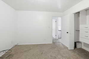 Unfurnished bedroom with light colored carpet and a textured ceiling