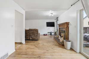 Living area with light wood-style flooring, a textured ceiling, and a fireplace