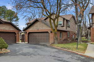 View of front of home featuring a front lawn, brick siding, asphalt driveway, and roof with shingles