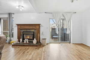 Living area with light wood-style flooring, a tile fireplace, and a textured ceiling