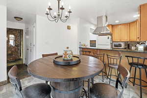 Dining room featuring a chandelier, light stone finish flooring, and a textured ceiling