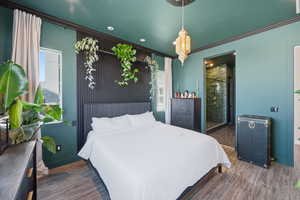 Bedroom featuring wood finished floors, ornamental molding, recessed lighting, and connected bathroom