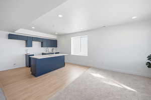 Kitchen with blue cabinetry, a kitchen island, light wood-style flooring, and recessed lighting