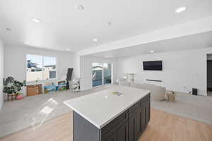 Kitchen featuring open floor plan, a kitchen island, light wood-style flooring, recessed lighting, and light colored carpet