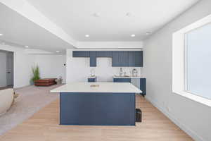 Kitchen with blue cabinetry, a center island, light wood-type flooring, and recessed lighting