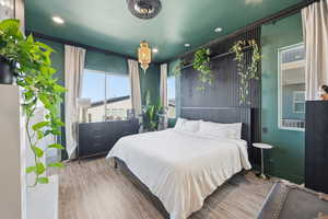 Bedroom featuring wood finished floors, recessed lighting, and crown molding